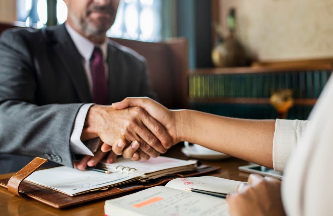 Handshake across a desk with documents
