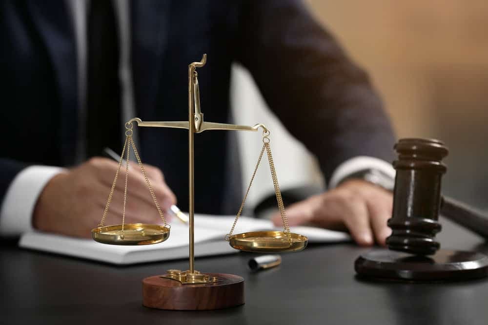Scales of justice beside a lawyer signing papers